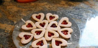A plate of heart shaped linzer cookies with raspberry filling.