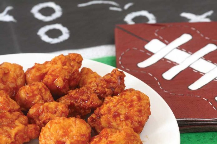 Boneless Buffalo Wings Boneless Buffalo Wings on a plate with Super Bowl decorations in the background