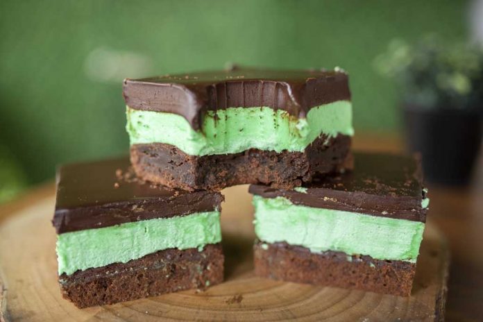 Chocolate Mint Brownies Three Chocolate Mint Brownies Stacked on a cutting board, showing the brownie, green filling layer and chocolate topping layer.