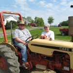A photo of a man on a tractor and woman beside him.