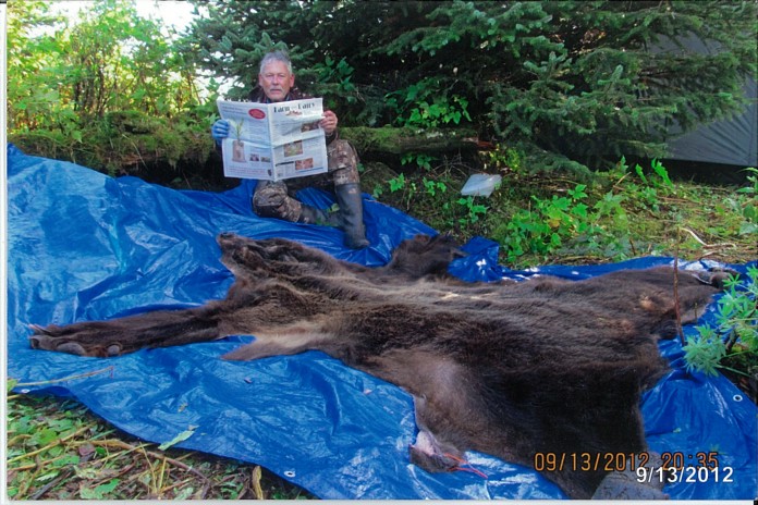 Bob Bergmeyer, of Canton, Ohio, takes a break to read Farm and Dairy while bear hunting in Cordova, Alaska. Bergmeyer spent his birthday in Alaska, hunting brown bear and moose. He got a bear his second day out, but while he was out hunting moose later, the bears ransacked his campsite. He still had a good time visiting with friends -- and he came home with a bear and about 50 pounds of halibut!