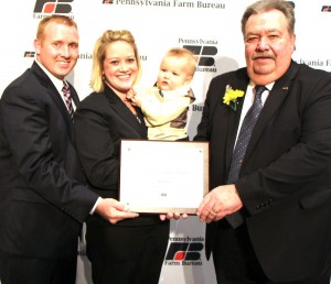 Cambria County farmers Tommy and Tracy Nagle, along with their young son Brady, receive Pennsylvania Farm Bureau’s 2013 Young Farmer and Rancher Achievement Award during PFB’s 63rd Annual Meeting in Hershey. Presenting the award is PFB President Carl Shaffer (right).