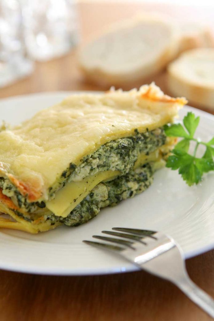 A piece of Four Cheese Spinach Lasagna on a white dinner plate.