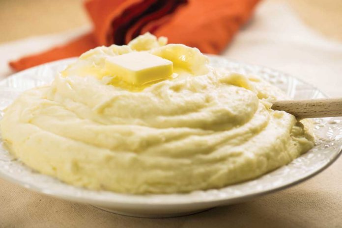 Cheesy Maple Mashed Potatoes A serving bowl of Cheesy Maple Mashed Potatoes with a pat of butter on top.