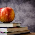 Female educators in Geauga County offer scholarship apple on top of books