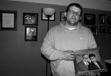 David Stanley’s last chance A man, David Stanley, stands holding his parents photo, behind him the wall is filled with other family photos. .