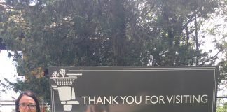 Lisa Kalas holding the Farm and Dairy Newspaper standing next to a sign that reads "Thank You For Visiting The House of the rock" in Madison, Wisconsin