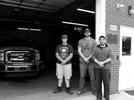 Three volunteer North Beaver Firefighters and Rescue workers stand in front of their station.