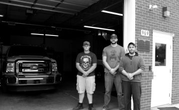 Three volunteer North Beaver Firefighters and Rescue workers stand in front of their station.