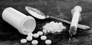 Pills, Fentynal Powder, and Heroin syringe sit on a table