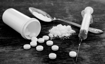 Pills, Fentynal Powder, and Heroin syringe sit on a table