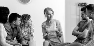 A diverse group of people sit and talk during a group counseling session.