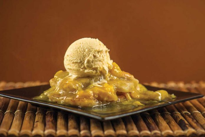 Slow Cooker Peach Cobbler A plate of Slow Cooker Peach Cobbler with a scoop of vanilla ice cream on top