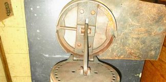 Richard Bader, of Middletown, New York, picked up Item No. 1125 at a yard sale. It is 9 inches in diameter, 6 1/2 inches in height when closed and weighs 12 pounds. There is a lever on the side that you can move to any hole on the disk. The peg on top has a handle and moves back and forth.