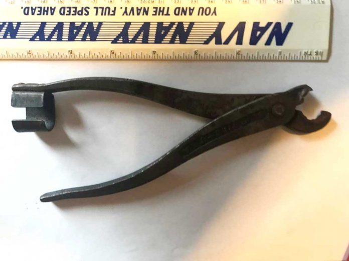 Hazard Item No. 1124 Metal plyer like item with a c-shaped piece on the end of one of the arms and curved pinchers that do not sit flat together.