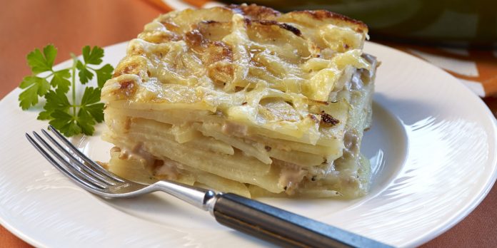 Potatoe & Swiss Cheese Au Gratin A serving of Potatoe & Swiss Cheese Au Gratin on a white plate with a sprig of parsley