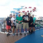 Cruising with the Swartz family and friends. The Swartz family and friends stand on the deck of their cruise ship with the waterslides in the background and a Farm and Dairy in their hands.