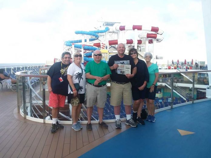 Vacation with Us - Swartz Family The Swartz family and friends stand on the deck of their cruise ship with the waterslides in the background and a Farm and Dairy in their hands.