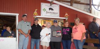 Darell Furlong stands with Ginny Barker and members of the hog committee after they recognized him with a plaque for his retirement.