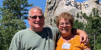 Tom White and Elizabeth Burrier stand in front of Mt. Rushmore with their Farm and Dairy newspaper in hand.