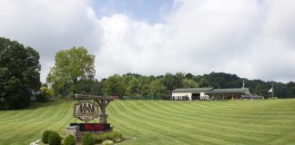 A sign for M&M Feed Supply with the store behind it.