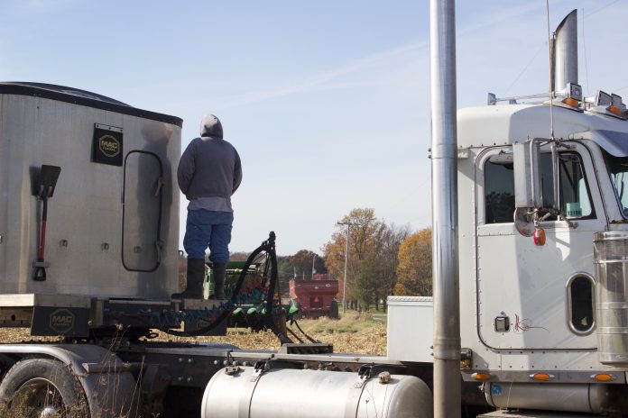 house_fire_harvest A farmer stands on a semi truck, watching combines harvest.