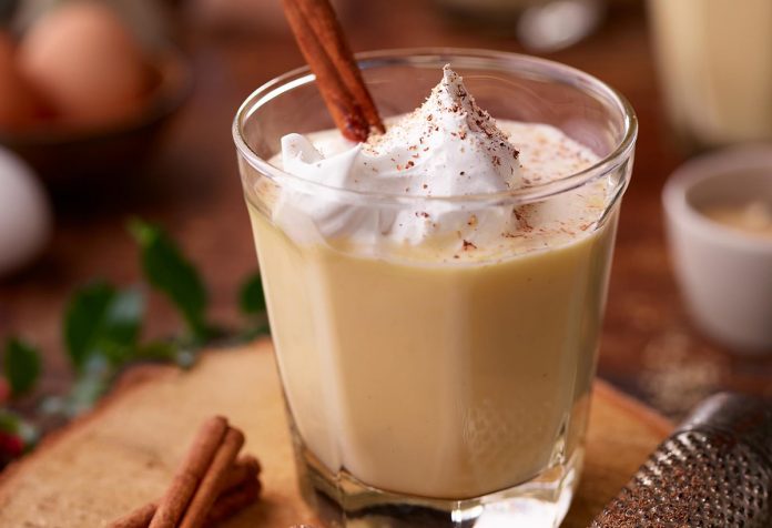 egg nog A glass of egg nog with whipped topping and a cinnamon stick garnish