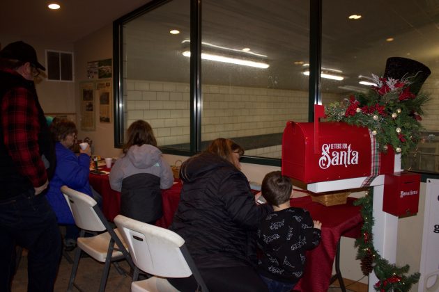 Children work on letters for Santa next to the mailbox.
