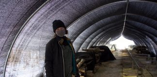 A woman stands in a tunnel under a shade cloth.