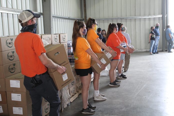 volunteers hold boxes of food