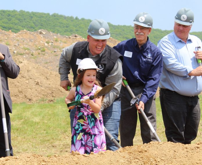 nicholas-meat little girl shoveling dirt while wearing a hard hat