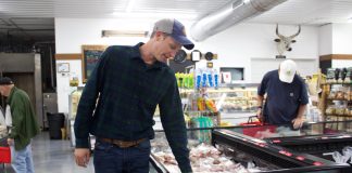 A man looks over cuts of meat in a store.