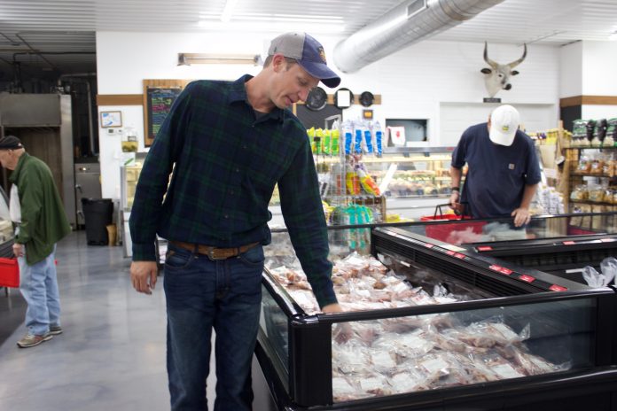 A man looks over cuts of meat in a store.