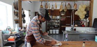 Hand Hewn Farm finds niche in hog butchering workshops guy wrapping up meat on a table