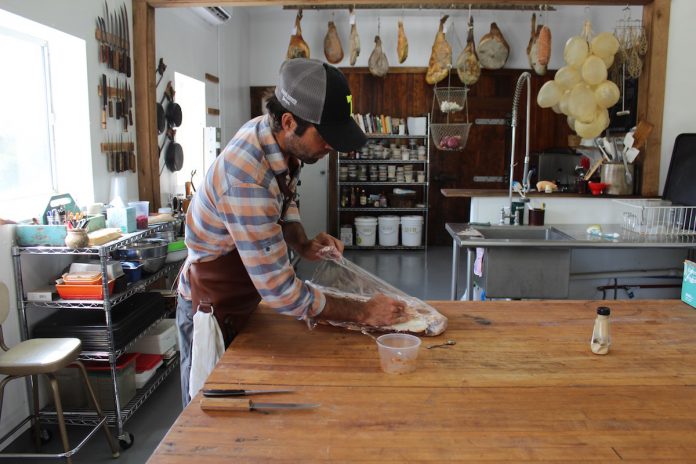 hand-hewn-3 guy wrapping up meat on a table