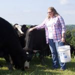Women in agriculture awardee applies NRCS knowledge to family farm A woman stands with several beef cattle after pouring out some grain for them in a pasture on her family farm, in West Virginia.
