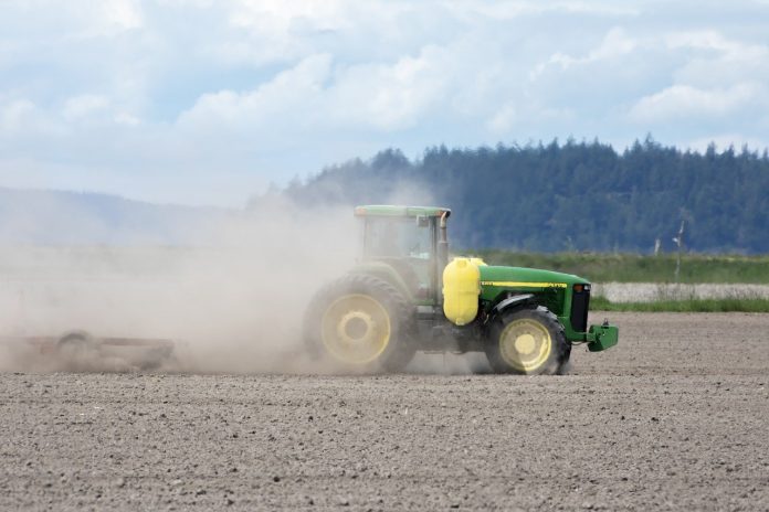 tractor stirring up dust in a field