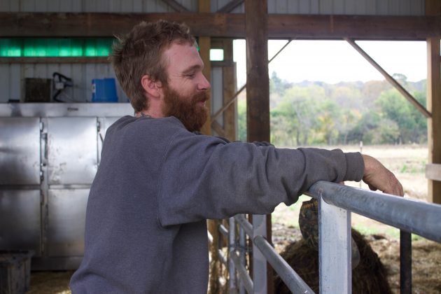 A farmer stands in a barn.