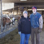 Fourth and fifth generations at Canon Dairy not afraid to try new things Two farmers stand in front of cows in a dairy barn.