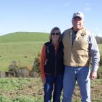 Two people stand on a farm.