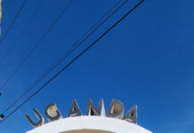 A Visit to the Ugandan Equator with Robin Tener Robin Tener stands inside the circular Ugandan Equator sign while holding a Farm and Dairy Newspaper.