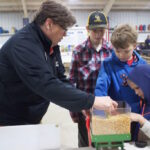 Columbiana County families learn about farm safety A woman demonstrates the hazards of grain to three children with a mini gravity wagon.