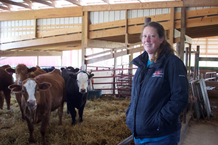 A woman stands near cows in a barn