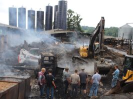 Columbiana County dairy farm loses barns, calves in fire men watch an excavator dig in remains of a barn fire