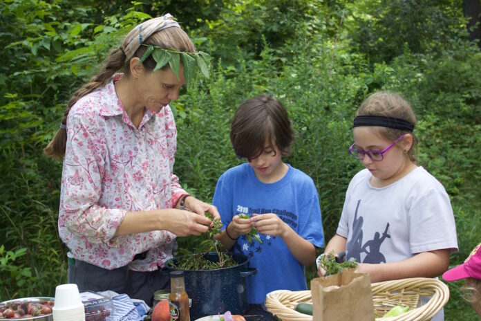 forest_school_5 a woman and two children cutting up ingredients for a salad.