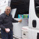 Porterfields continue legacy in ag with farm, ice cream shop A man holds a cup of ice cream next to a van with freezers inside it and a cow pattern painted on the outside.