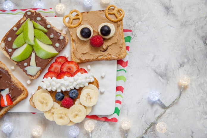 Funny Christmas faces toasts with banana, strawberry and blueberry