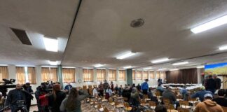 people sitting at chairs facing away from the camera with a floor