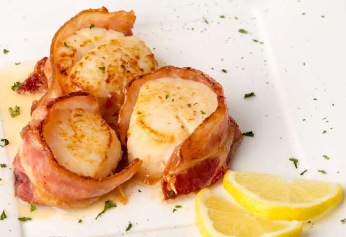 Bacon Wrapped Scallops on White Plate with Lemon Slices and Gree