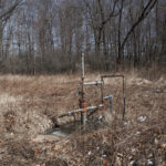 Penn State offers landowners $100 per undocumented well A well head sits in a brushy area next to some trees